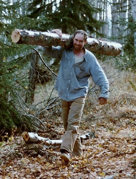 Sam carrying a log that will be used for firewood.